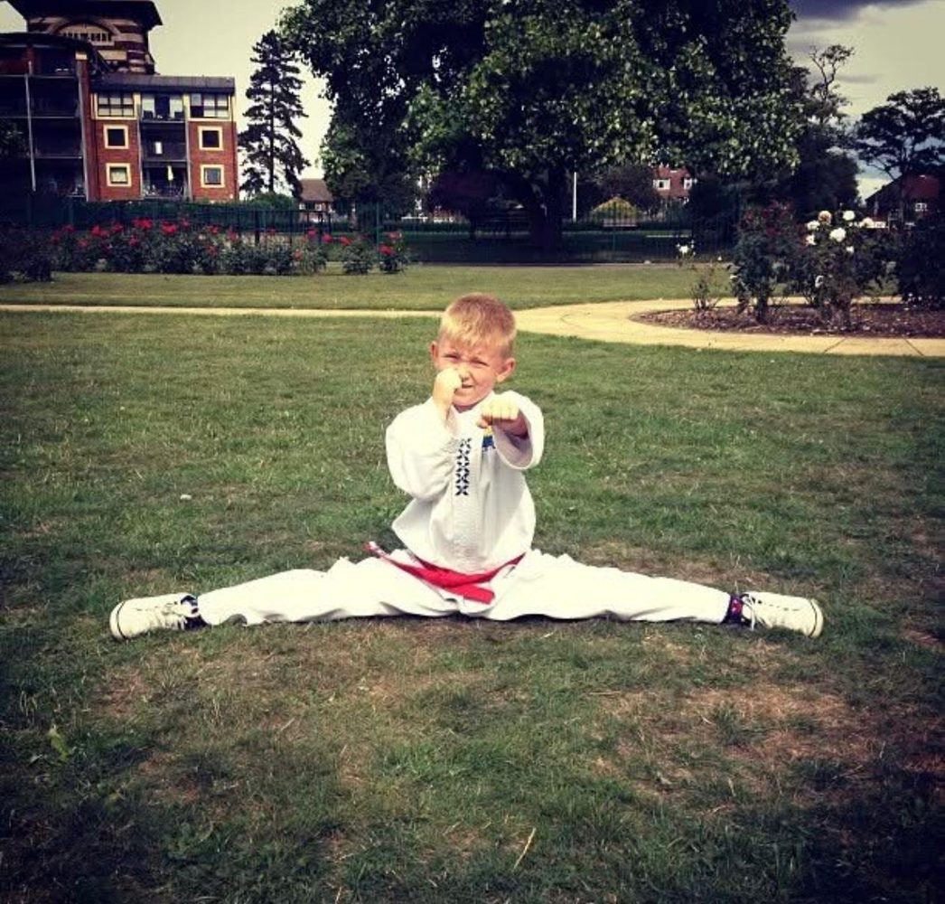 Young student in a split with fists up in a park